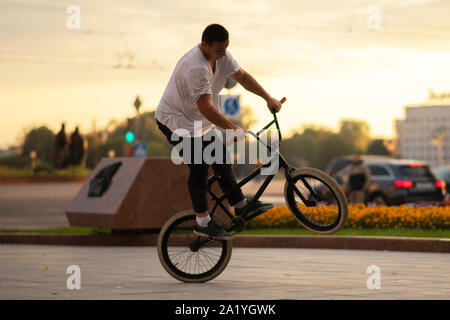 The guy performs a BMX stunt while standing on the rear wheel. Stock Photo