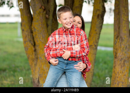 Mom squatting, hugs a smiling son. Stock Photo