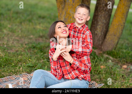 The son gently hugs mom on the shoulders, both smiling happily. Stock Photo