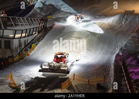 Two snowcat ratrack machines making night show performance on snow pister hill at alpine skiing resort Ischgl in Austria Stock Photo