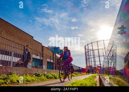 woman on pushbike cycling along a canal towpath in London Stock Photo