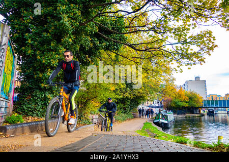Commuter cycles along towpath on London canal Stock Photo