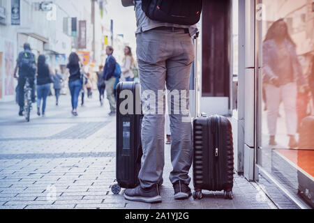 Unrecognizable young man traveling with suitcases, city street, travel and tourism concept Stock Photo