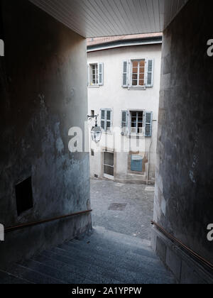 Medieval paved street and an old house with windows with wooden shutters seen from a narrow alley with stairs in the Old Town of Geneva, Switzerland. Stock Photo