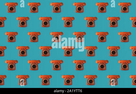 Seamless pattern of an orange retro style telephone, isolated on a blue background Stock Photo
