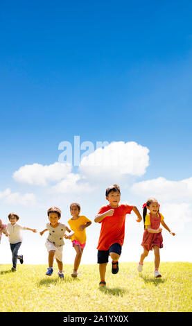 Multiethnic group of school children running on the grass Stock Photo