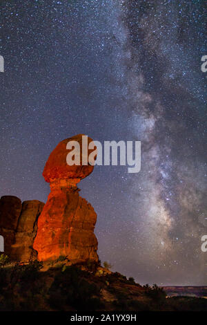 Iconic Balanced Rock illuminated against a star-filled Milky Way in Arches National Park in Moab, Utah. Stock Photo