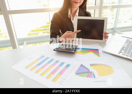 businesswoman showing blank screen tablet with computer on table Stock Photo