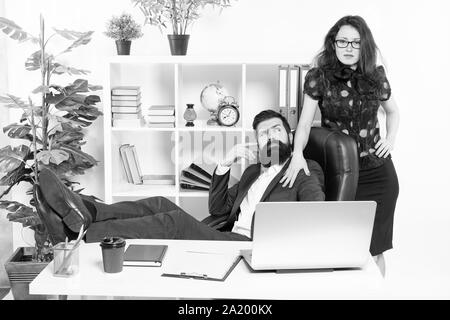 Lazy boss office. Offer massage. Man bearded hipster boss sit in leather armchair office interior. Boss and secretary girl at workplace. Relations at work. Business people and staff concept. Stock Photo