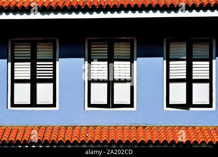 Exterior of Singapore shop house with blue facade and antique black and white wooden shutters in historic Kampong Glam Stock Photo