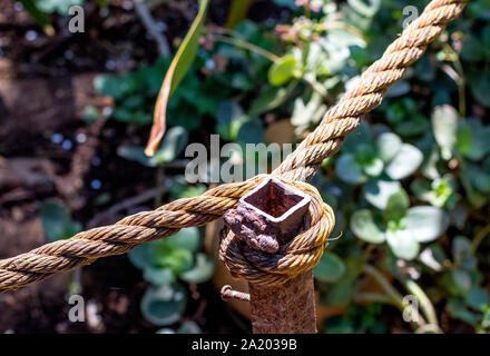 A thick rope looped around a rusted stake image with copy space in horizontal format Stock Photo