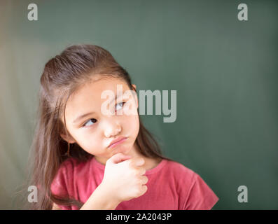 little girl standing against chalkboard background Stock Photo