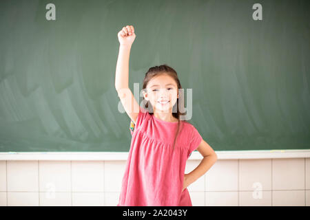 happy little girl standing against chalkboard background