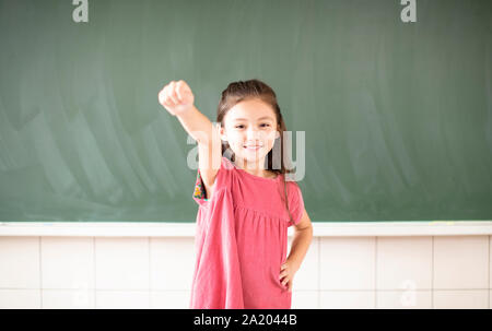 happy little girl standing against chalkboard background Stock Photo
