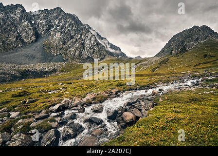 Dramatic scenery of foggy mountains and river in Altyn Arashan George, Kyrgyzstan Stock Photo