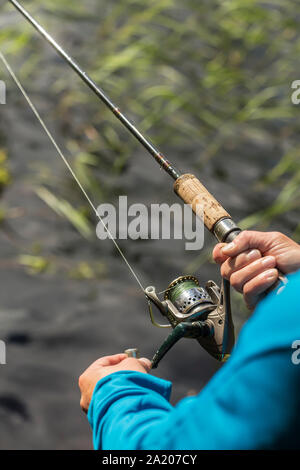 Man fishing on spinning, sunny summer day at the lake Stock Photo
