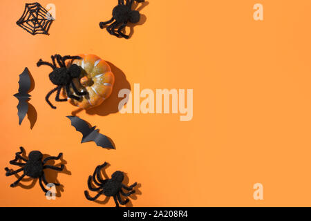 Halloween border with black spiders and spiderweb on orange background. Flat lay style, top view, copy space. Party accessories. Stock Photo