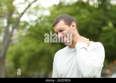 Man suffering neck ache complaining standing alone in a park Stock Photo
