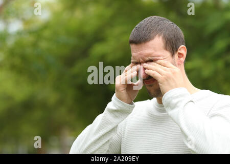 Man suffering itching scratching eyes standing alone in a park Stock Photo