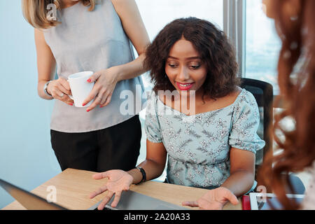 Confused pretty young business lady having some problems with program installed on her laptop Stock Photo