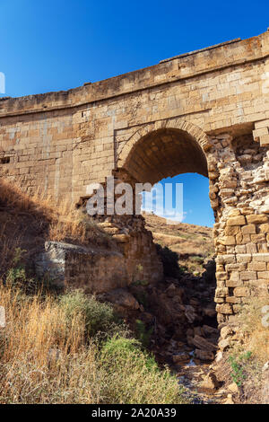 Old dilapidated stone bridge over a small mountain river Stock Photo