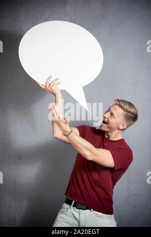 Joyful man presenting white empty speech balloon. Stock Photo