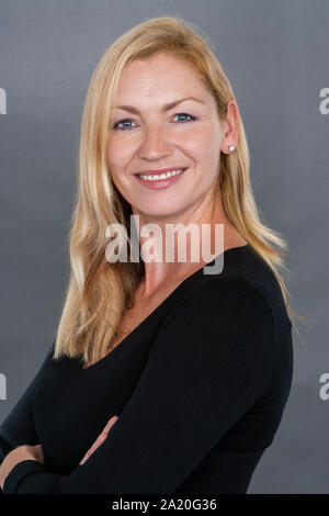 Studio portrait headshot of attractive happy smiling middle aged blonde woman in her thirties or forties Stock Photo