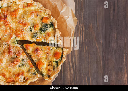 Delicious quiche or tart with vegetables, spinach and cheese on the rustic wooden table Stock Photo