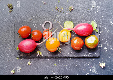 Top view at fresh organic vegetables on slate stone tray with spices aside closeup dark concept photo
