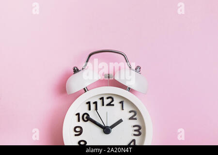 Retro analog alarm clock on pastel pink background Stock Photo