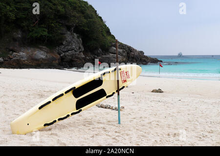 Surf rescue board on a tropical beach in a picturesque bay with red flags. Rescue of drowning in stormy sea, ban on swimming Stock Photo