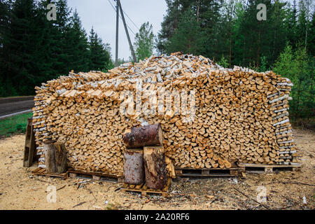 Large pile of chopped fire wood, folded exactly crushed firewood. The stack of firewood is prepared for the winter or furnace for saunas. Stock Photo