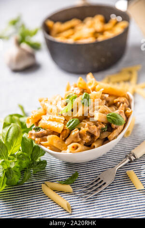 Pasta penne with chicken pieces mushrooms basil and parmesan cheese  Italian food in white bowl on kitchen table