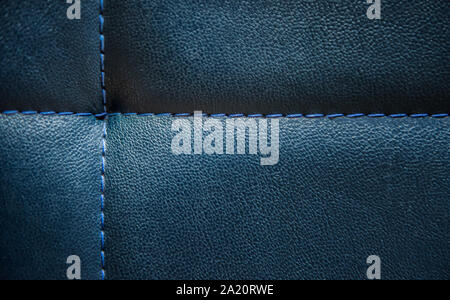 Bright shiny dark blue artificial textured leather stitched with blue thread. Close-up of sofa surface. View from above. Highly detailed background wi Stock Photo