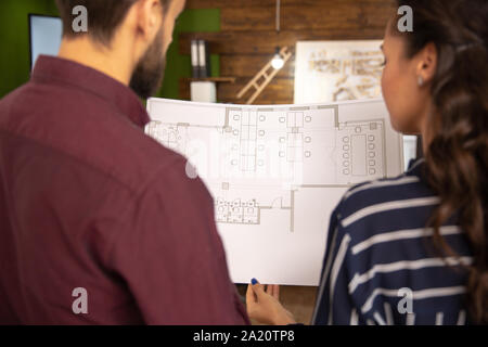 Rear view with female and male architects talking while holding a blue through hand. Professional discuss Stock Photo