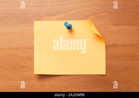 Paper memo attached to a wooden table with a blue thumbtack Stock Photo