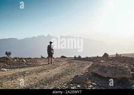 Young tourist with backpack on mountain road at sunset. Jebel Akhdar, Oman. Stock Photo