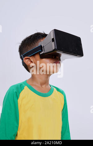 Schoolboy standing using virtual reality glasses on white background Stock Photo
