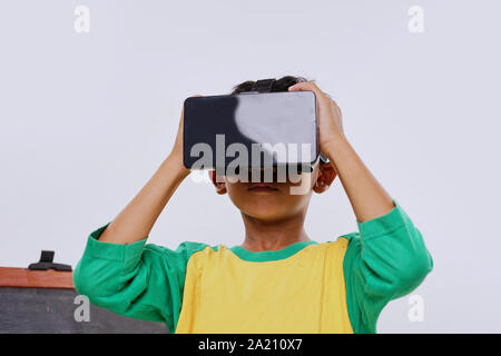 Schoolboy standing using virtual reality glasses on white background Stock Photo