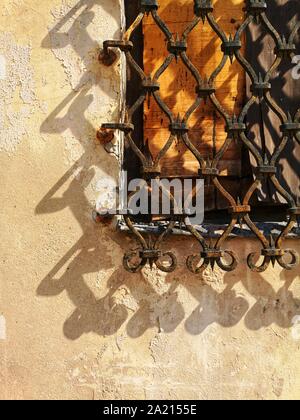 old barred window casting shadow on the wall Stock Photo