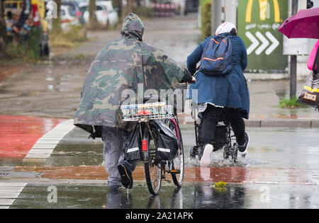 Hanover, Germany. 30th Sep, 2019. Passers-by walk across a road in rain and storm. Stormy low 'Mortimer' sweeps across northern Germany. Credit: Julian Stratenschulte/dpa/Alamy Live News Stock Photo