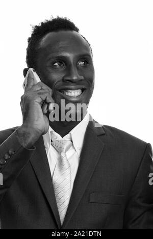 Face of thoughtful young happy African businessman smiling while talking on mobile phone Stock Photo