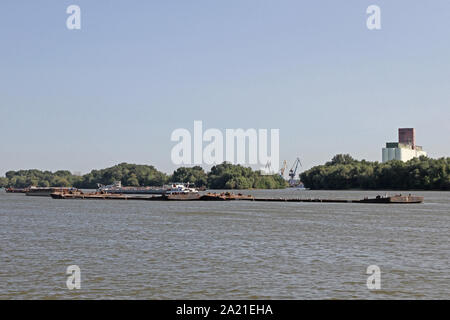 View of tanker on Danube River near Belgrade with trees on shore with grain silos and the Port of Belgrade behind it, Danube River, Serbia. Stock Photo