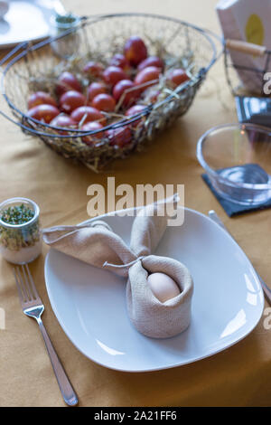 Real family table set for Easter breakfast in traditional Polish home. Basket filled with eggs colored with onion skins. Stock Photo