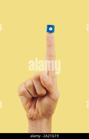 Blue dice with one dot on index finger of person, gambling and good luck concept Stock Photo
