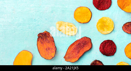 A panorama of dry fruit and vegetable chips, shot from the top on a vibrant teal blue background with copy space Stock Photo