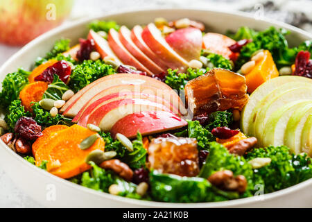 Winter salad with apple, pumpkin, cranberries, honey and seeds in a white plate. Healthy vegan food concept. Stock Photo