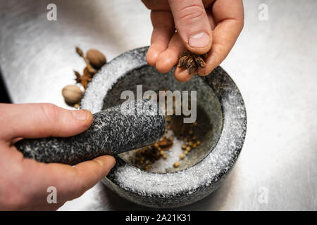 Crushing spices in pestle and mortar in kitchen Stock Photo