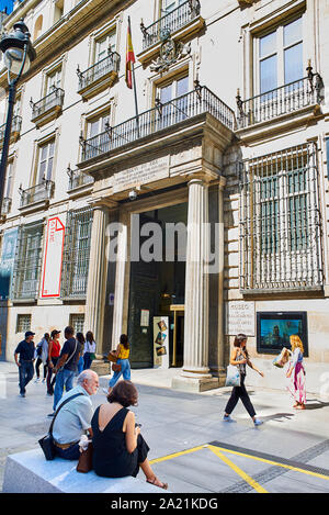 Tourists walking in front of principal facade of The Royal Academy of Fine Arts of San Fernando. View from Alcala street. Madrid, Spain. Stock Photo