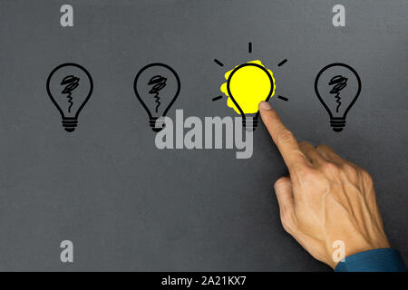 Creative ideas concept. Conceptual different thinking or leadership. A businessman hand choose a one shining light bulb and many light bulb goes out o Stock Photo